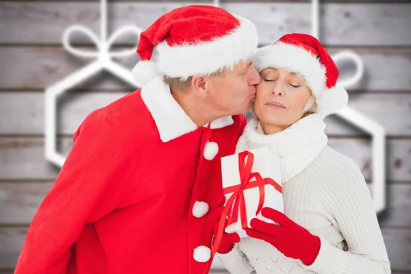 Man in santa hat kussen vrouw bedrijf cadeau — Stockfoto