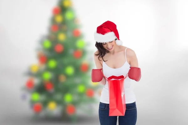 Žena v santa hat pohledu na nákupní taška — Stock fotografie