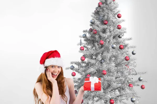 Frau mit Weihnachtsmütze hält ein Geschenk in der Hand — Stockfoto