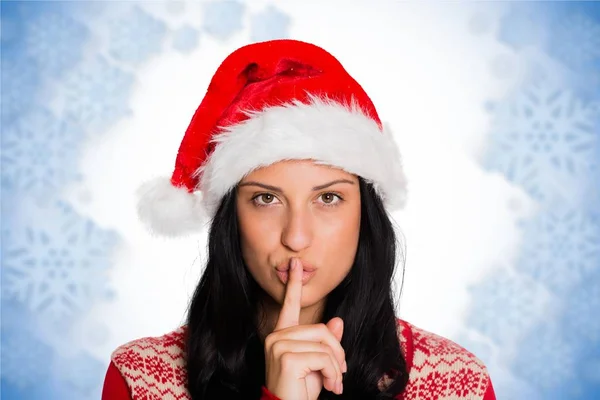 Vrouw in kerstmuts met een vinger op de lip — Stockfoto