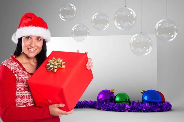 Frau mit Weihnachtsmütze hält Weihnachtsgeschenk in der Hand — Stockfoto