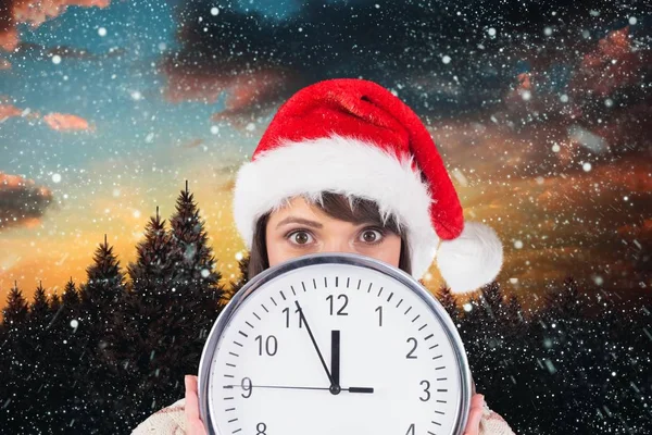女人在圣诞老人的帽子，拿着墙上的钟 — 图库照片
