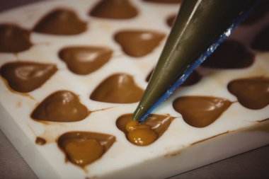Filling a chocolate mould with a piping bag clipart