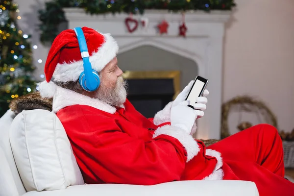 Kerstman met behulp van mobiele telefoon thuis — Stockfoto