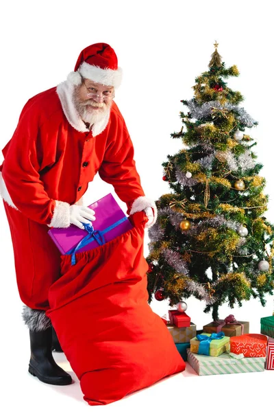 Santa claus zetten cadeautjes in christmas zak — Stockfoto