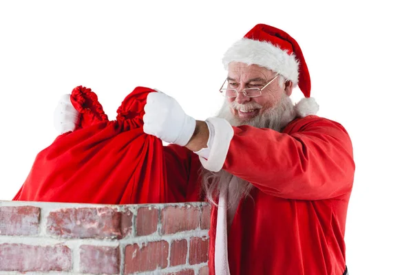 Weihnachtsmann legt Geschenkbox in Schornstein — Stockfoto