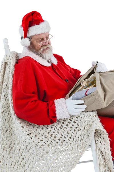 Weihnachtsmann sitzt auf Stuhl und betrachtet Geschenke — Stockfoto