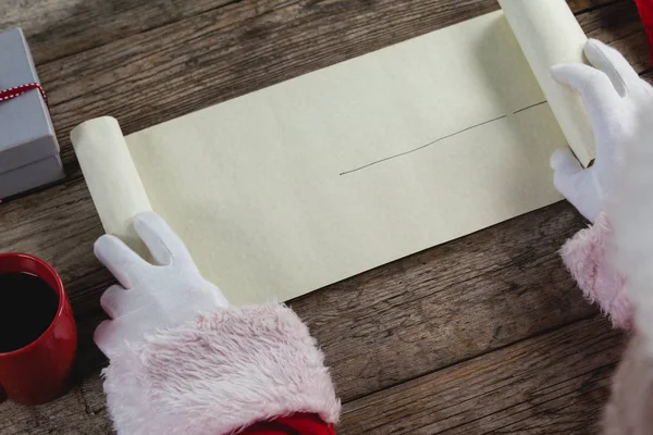 Weihnachtsmann öffnet Schriftrolle — Stockfoto