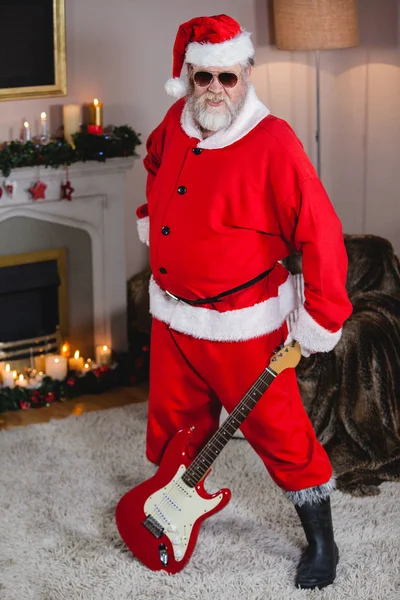 Улыбающийся Санта Клаус стоит с гитарой — стоковое фото