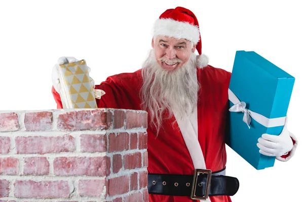 Санта Клаус кладет подарочную коробку в дымоход — стоковое фото