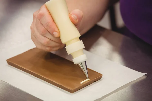 Worker writing with piping bag on chocolate — Stock Photo, Image