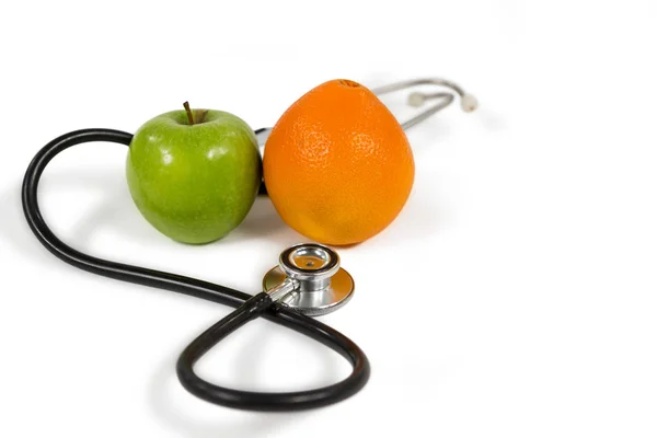 Стетоскоп, апельсин, яблоко на белом — стоковое фото