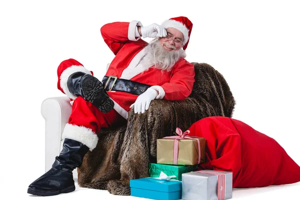 Weihnachtsmann sitzt auf Sofa mit Sack voller Geschenke — Stockfoto