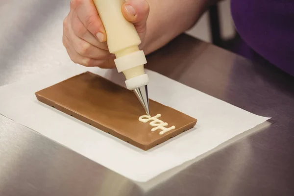 Worker writing happy birthday on chocolate — Stock Photo, Image