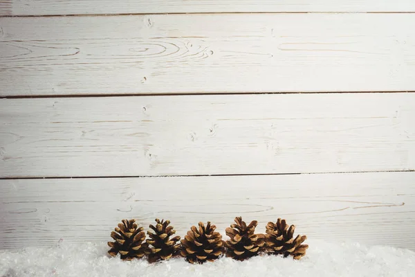 Украшение соснового конуса на поддельном снегу — стоковое фото