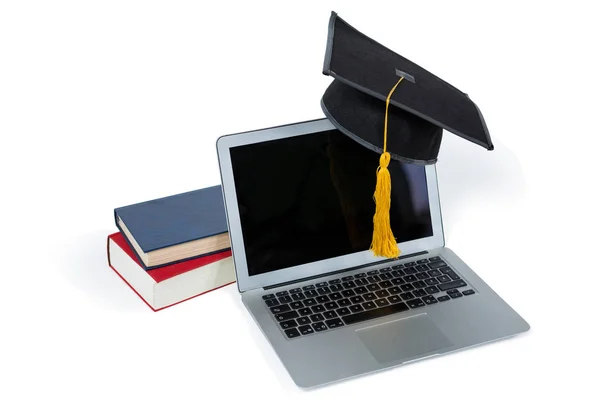 Laptop met mortarboard en boeken — Stockfoto