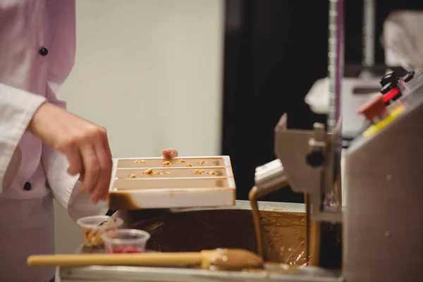 Lavoratore spruzzando dolciumi su stampo di cioccolato — Foto Stock