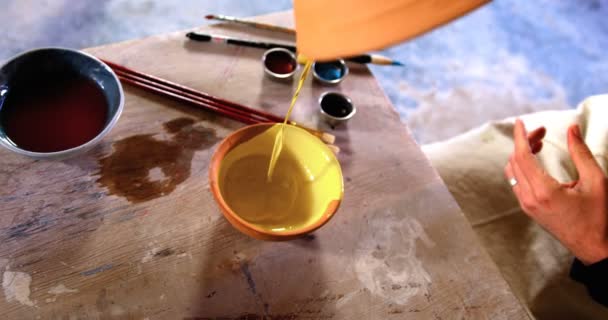 Oleiro macho derramando aquarela na tigela na oficina de cerâmica — Vídeo de Stock
