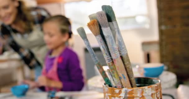 Mother assisting daughter in painting bowl — Stock Video