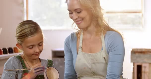 Мать ассистирует дочери в покраске чаши — стоковое видео