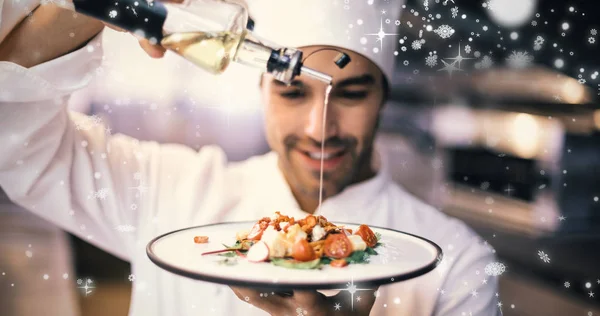 Knappe chef-kok gieten van olijfolie op de maaltijd — Stockfoto