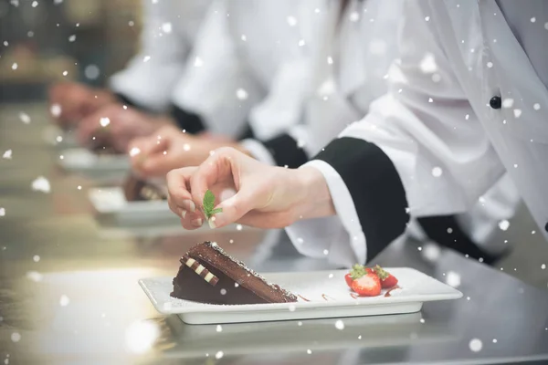 Chefs in a row garnishing dessert plates — Stock Photo, Image