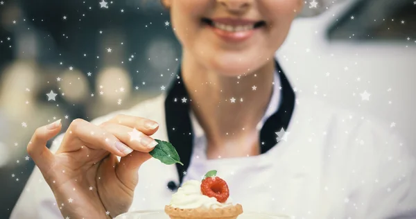 Chef putting mint leaf on little cake — Stock Photo, Image