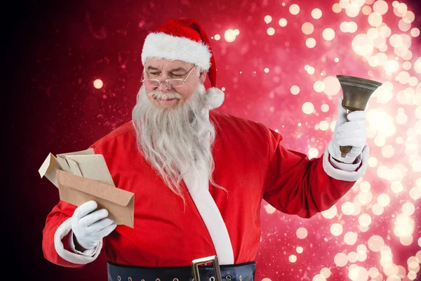 Санта Клаус читает конверт с колокольчиком — стоковое фото