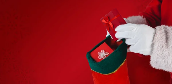 Santa putting presents in christmas stockings — Stock Photo, Image