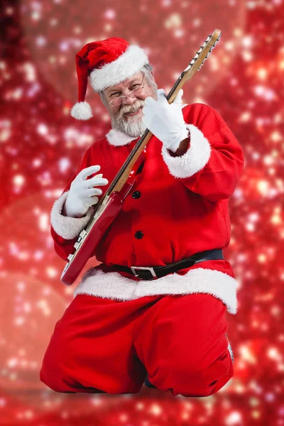 Santa claus kneeling and playing guitar — Stock Photo, Image