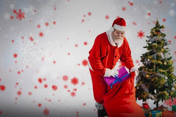 Weihnachtsmann packt Geschenke in Tüte — Stockfoto