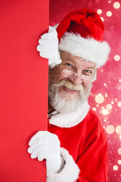Santa claus gluren van rode bord — Stockfoto