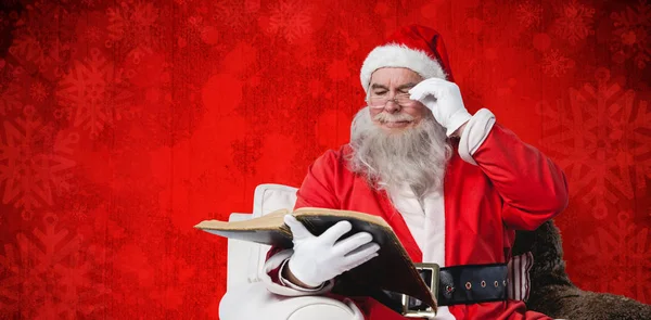 Weihnachtsmann liest Bibel auf Sessel — Stockfoto