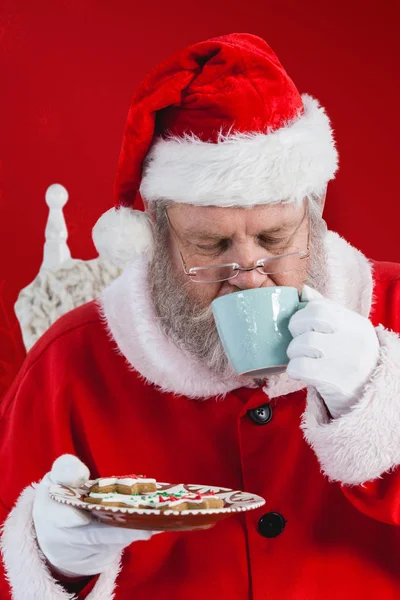 Santa claus drinking coffee with cookies — Stock Photo, Image
