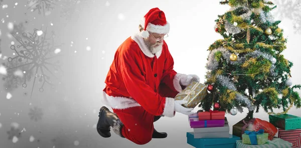 Santa Claus arreglando regalos en el árbol — Foto de Stock