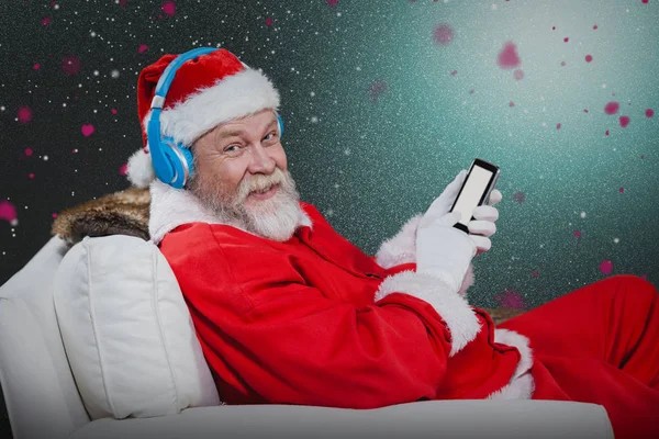 Święty Mikołaj z słuchawek i telefonu komórkowego — Zdjęcie stockowe