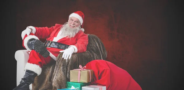 Санта сидит на диване с подарком на Рождество — стоковое фото