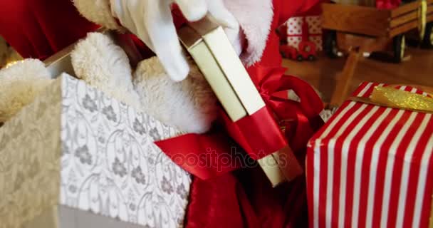 Санта-Клаус вытаскивает подарочные коробки из мешка — стоковое видео
