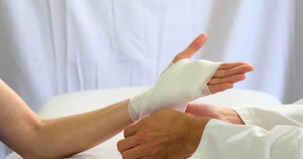 Физиотерапевт накладывает повязку на поврежденную руку пациента — стоковое видео