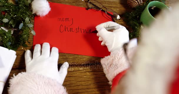Weihnachtsmann schreibt frohe Weihnachten auf Karte — Stockvideo