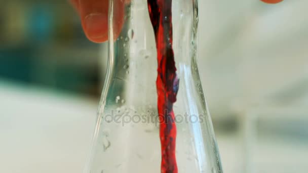 Scientist pouring test tube liquid into a erlenmeyer flask — Stock Video