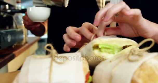 Kellnerin wickelt Sandwich mit Wachspapier ein — Stockvideo