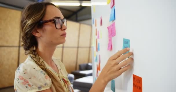 Frau klebt Zettel auf Whiteboard — Stockvideo