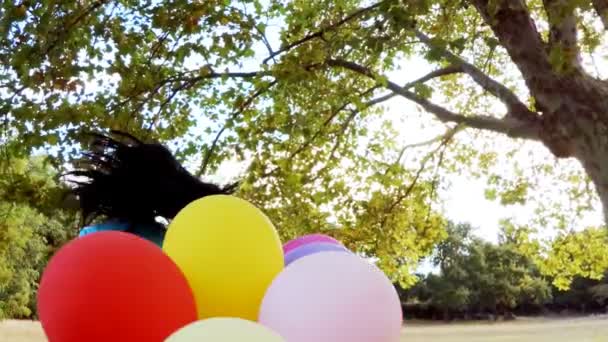 Leende flicka som leker med ballonger i park — Stockvideo