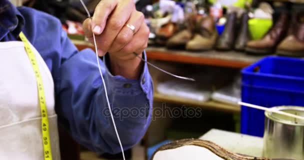 Schoenmaker draad in de naald zetten — Stockvideo
