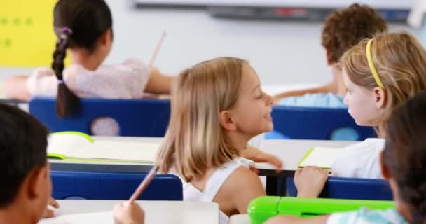 Schulmädchen flüstert ihrer Freundin im Klassenzimmer ins Ohr — Stockvideo