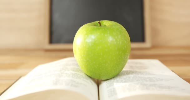 Açık kitap ile yeşil elma — Stok video