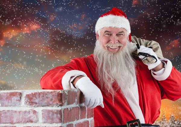 Santa med gåva säck lutande på chinmey — Stockfoto