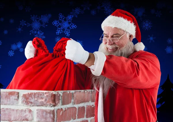 Santa claus placing gift sack into chimney — Stock Photo, Image