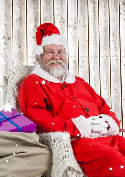 Santa zitten op stoel met geschenken — Stockfoto